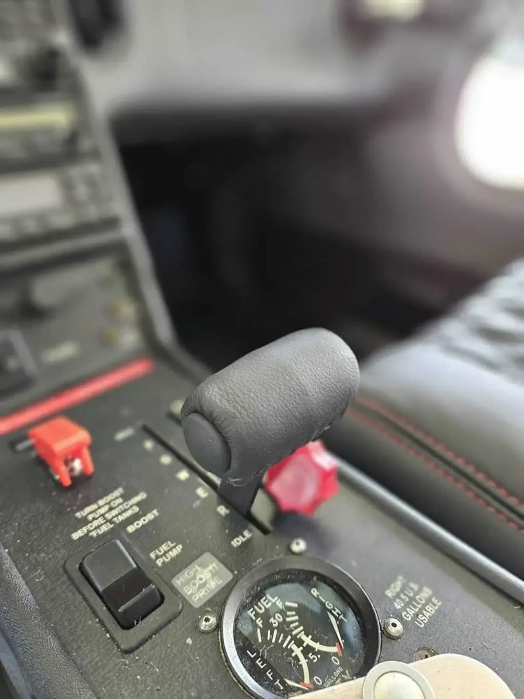 A close-up of an aircraft's throttle quadrant with a fuel gauge and various switches.