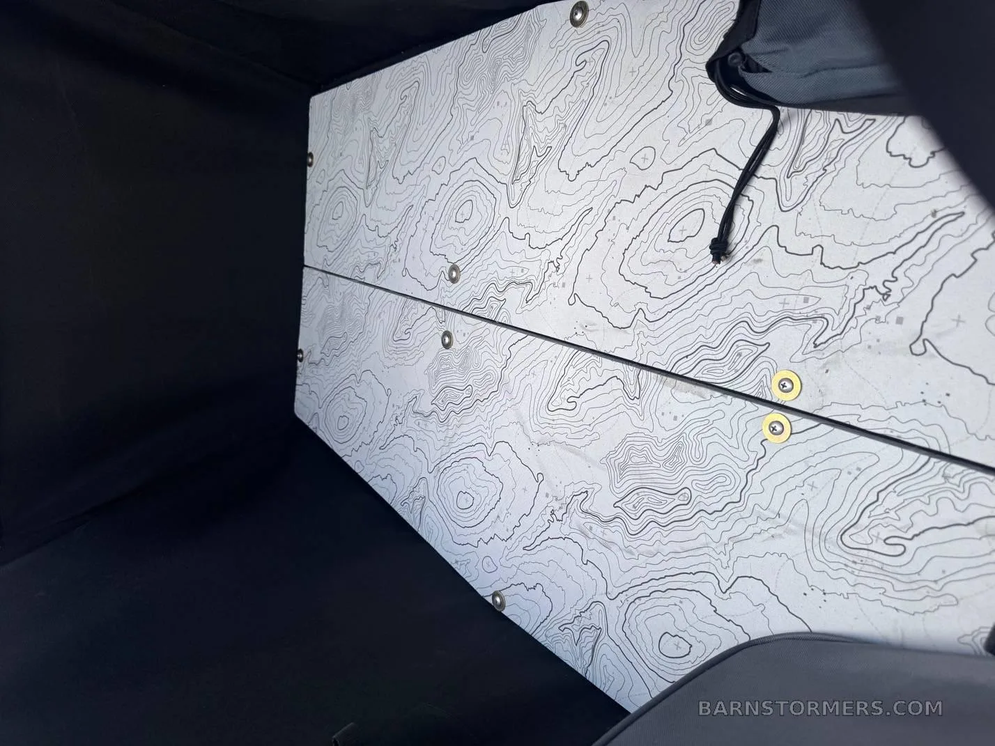 An interior view of an aircraft's cargo or storage compartment, lined with a white and black topographical map pattern.