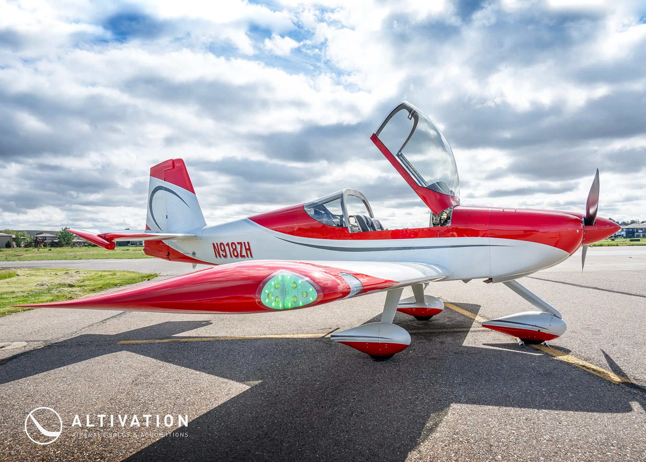 The red and white N918ZH aircraft with its canopy open, showing green lights on the wingtip.