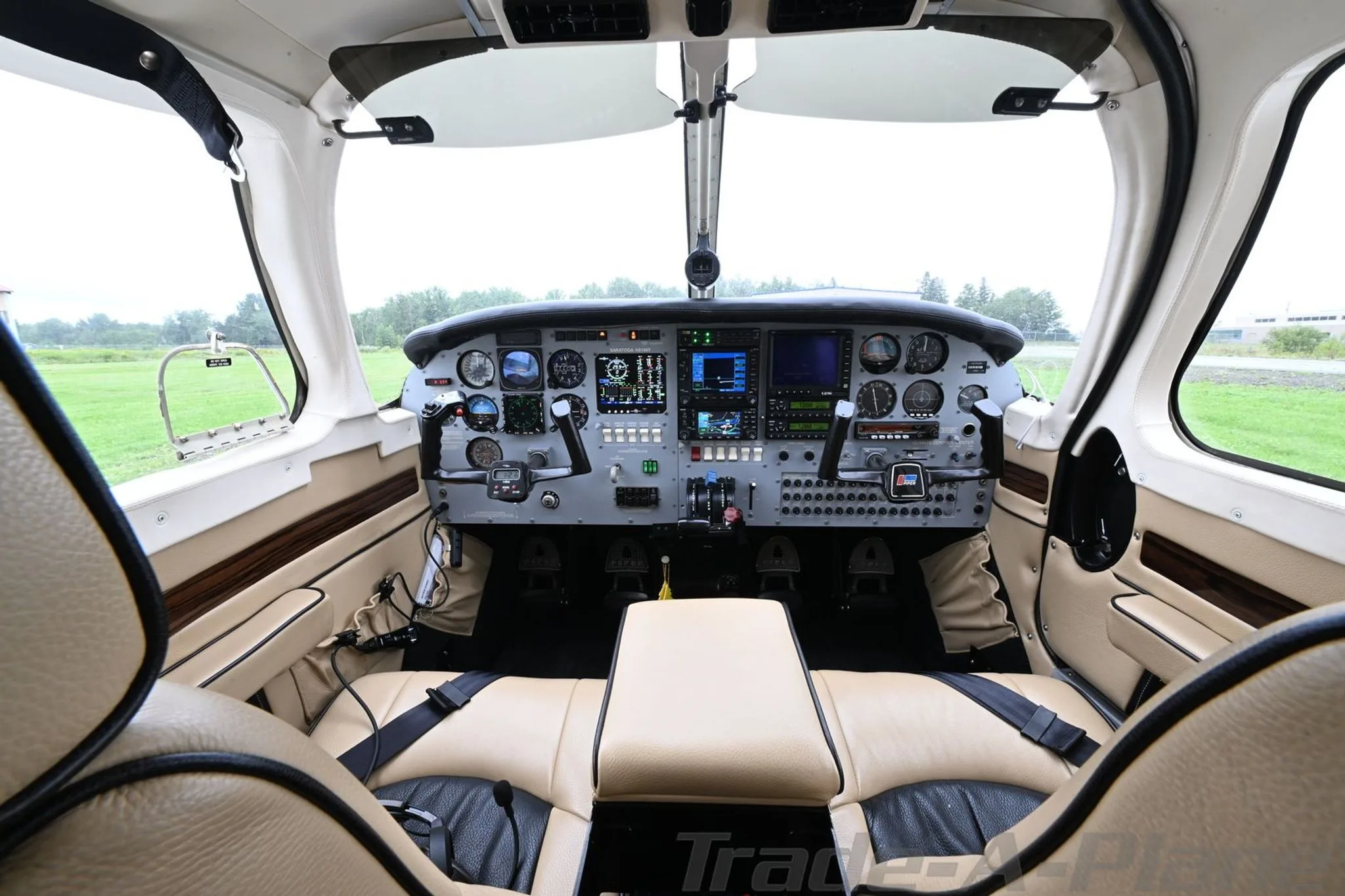 The cockpit of a Piper Saratoga with modern avionics and tan and black seats.