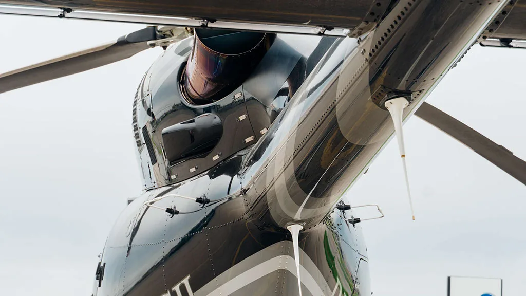 A close-up view of the tail boom and engine exhaust of the black and silver Bell 427 helicopter.