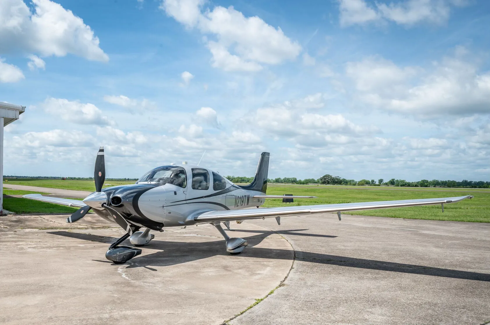 A front-side view of the silver and black Cirrus SR22T GTS Platinum aircraft N219TW on an airfield.