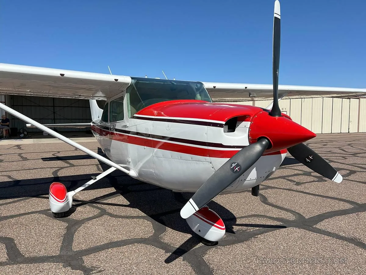 A front view of a white and red Cessna Skylane II showing its propeller and nose cone.