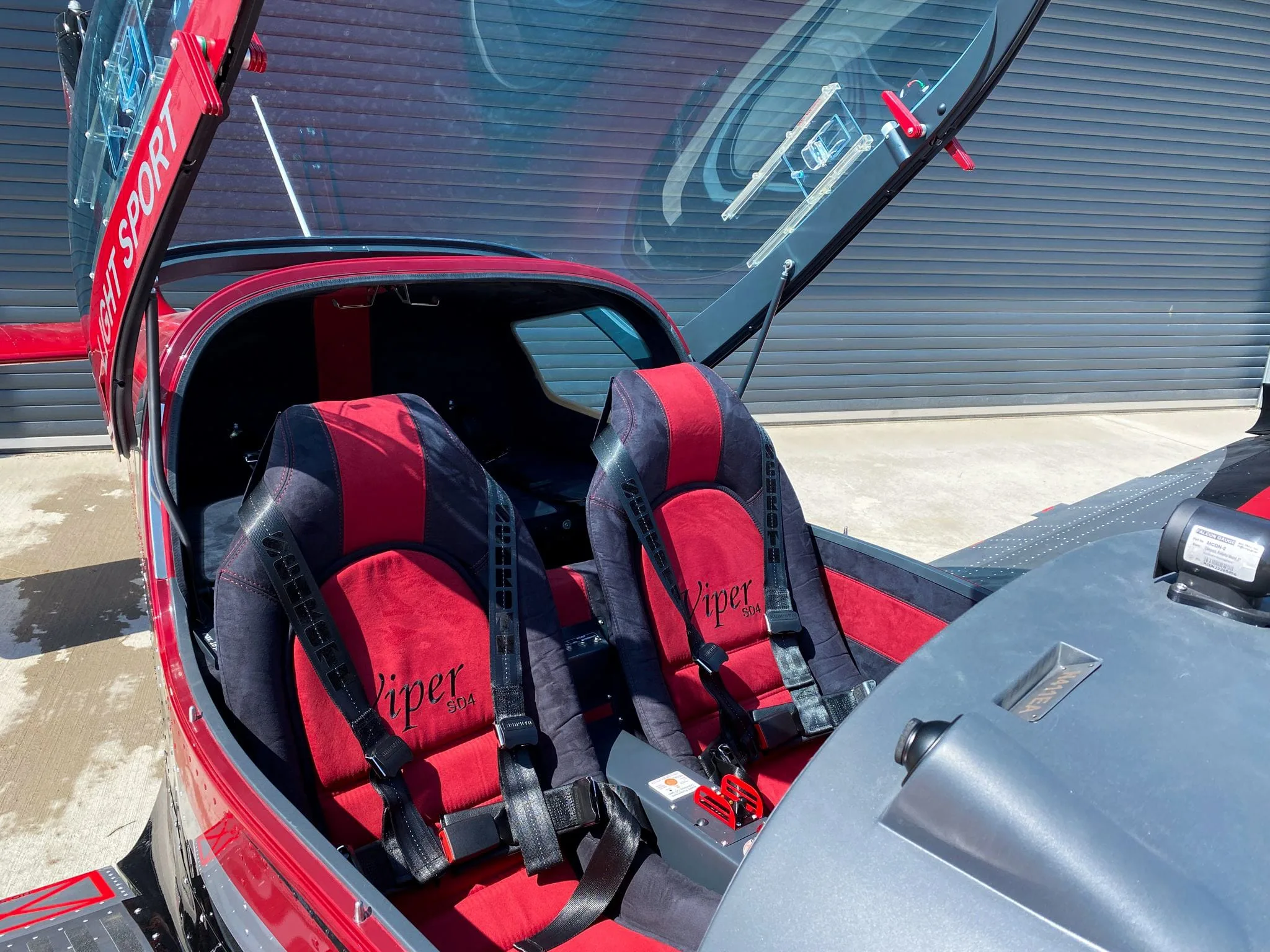 The red and black interior of a Viper SD4 light sport aircraft, showing two seats with "Viper" branding and harnesses.