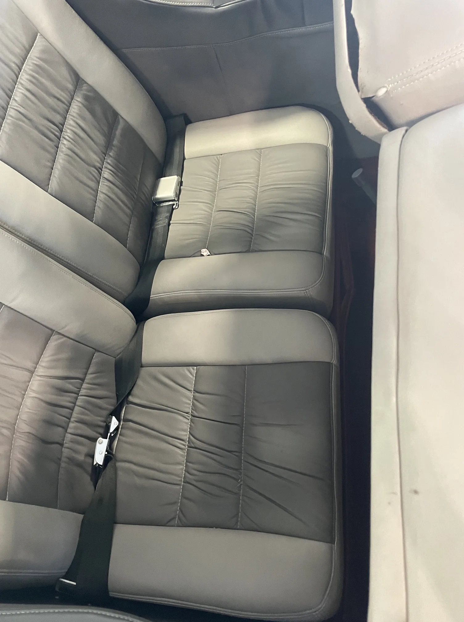 Two rows of grey and light grey pleated leather aircraft passenger seats.