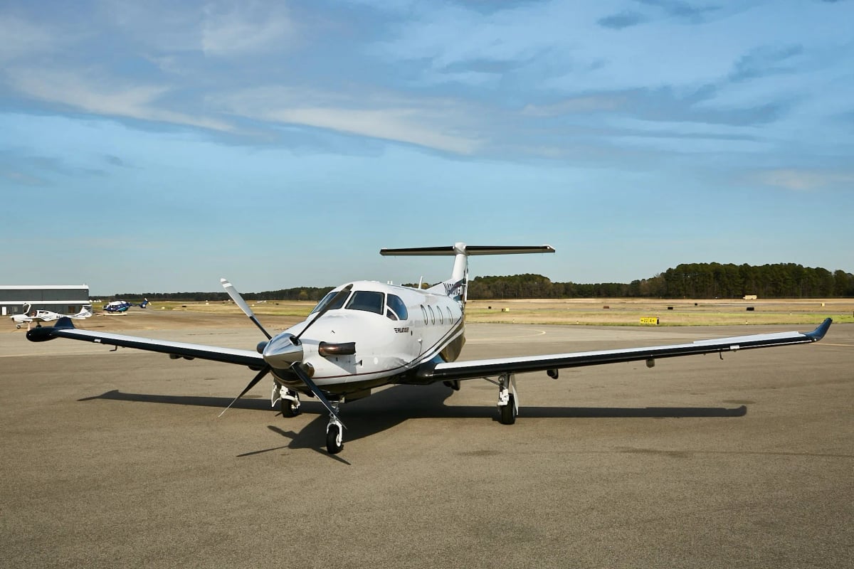 Pilatus PC-12NG on the tarmac with other aircraft in the background.
