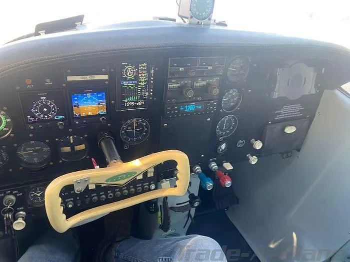 The cockpit of an aircraft featuring a modern instrument panel with digital displays and a light-colored control yoke.