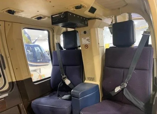 The rear cabin interior of the helicopter with two blue fabric seats and seatbelts.