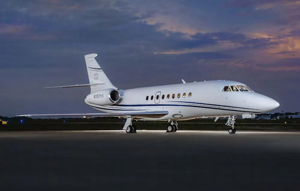 A Dassault Falcon 2000 business jet, registration N192HA, parked on an tarmac at sunset.