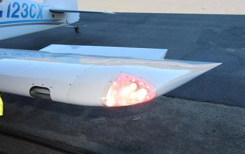 A close-up view of the right wingtip of the N123CX aircraft, showing a bright red navigation light.