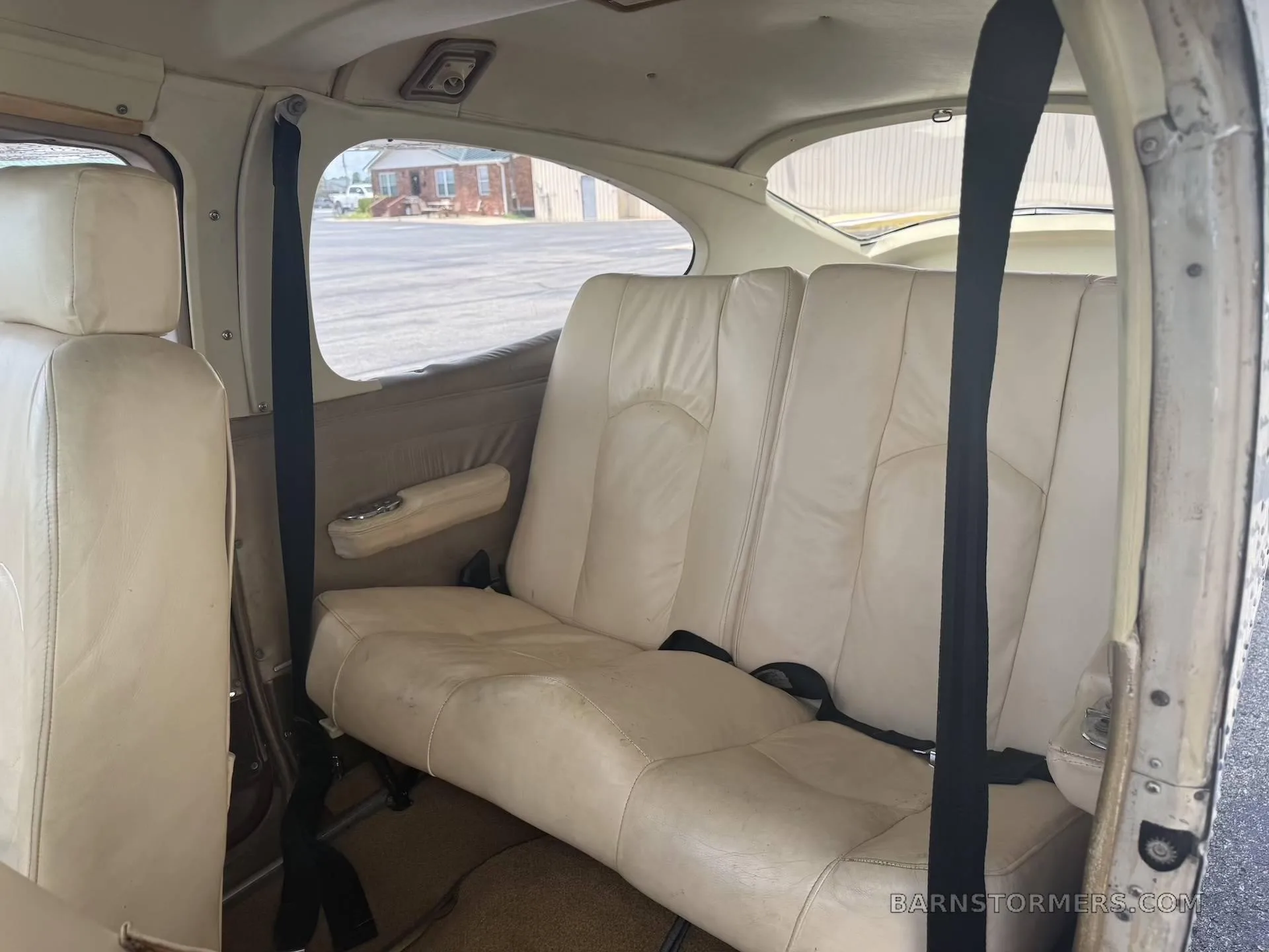 The light tan leather rear bench seat of a small aircraft cabin.