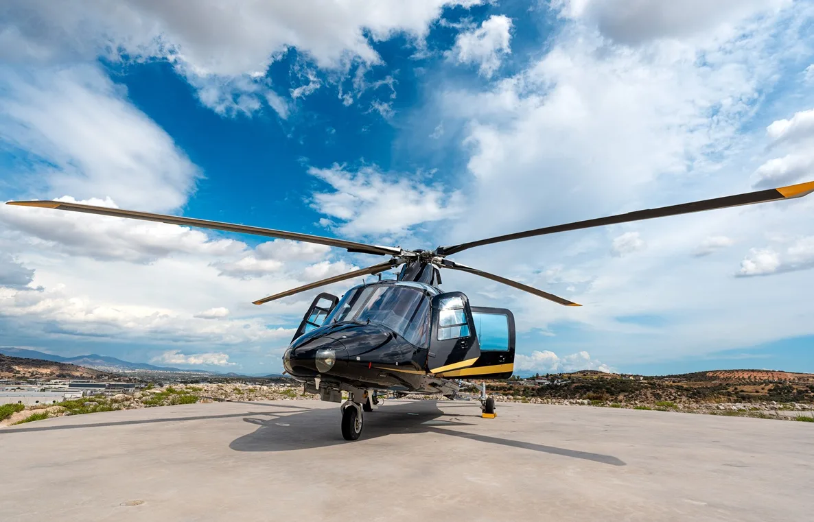 Front view of a black and gold helicopter parked on the tarmac.