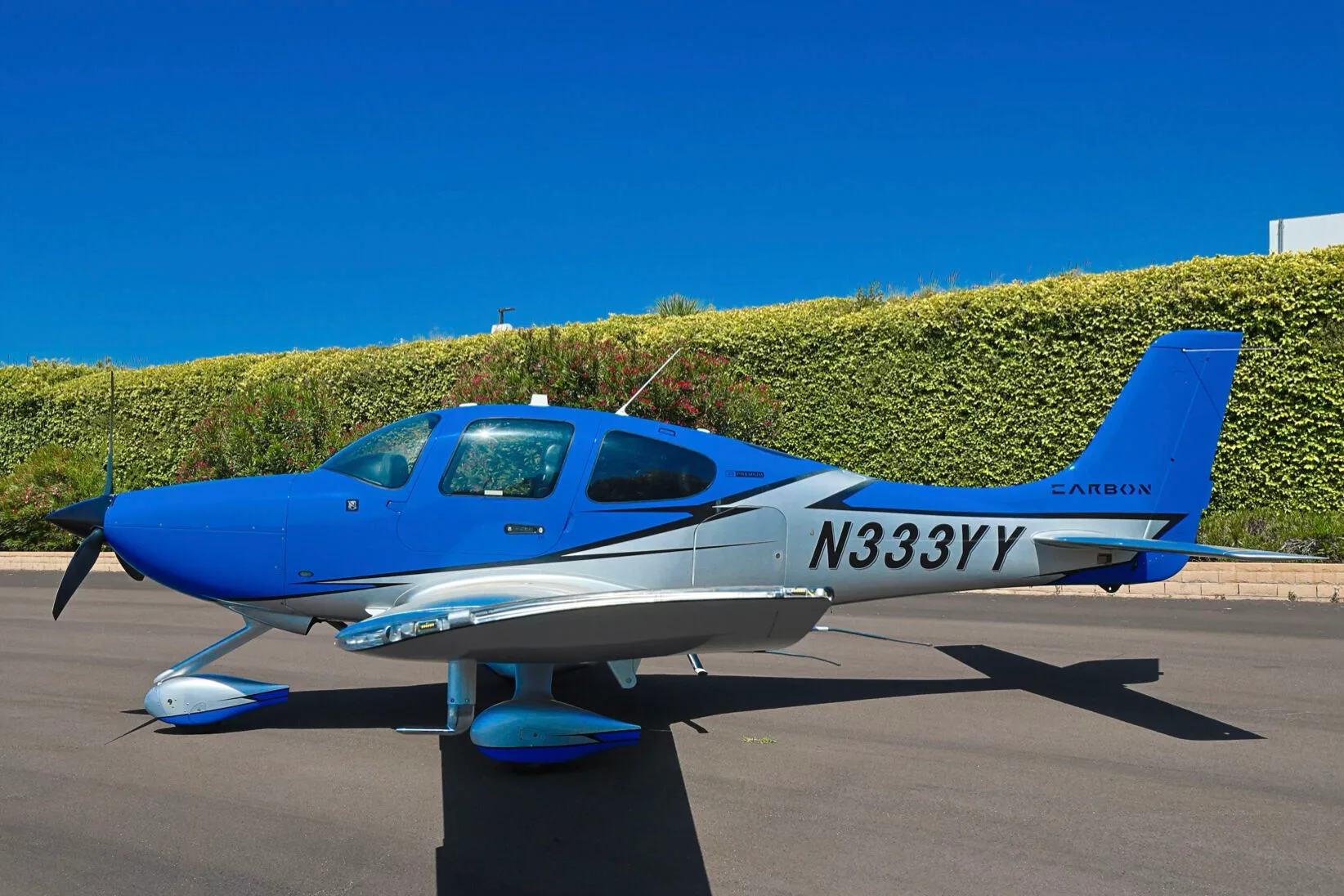 A side view of the blue and silver Cirrus SR20 aircraft N333YY parked on an asphalt ramp.