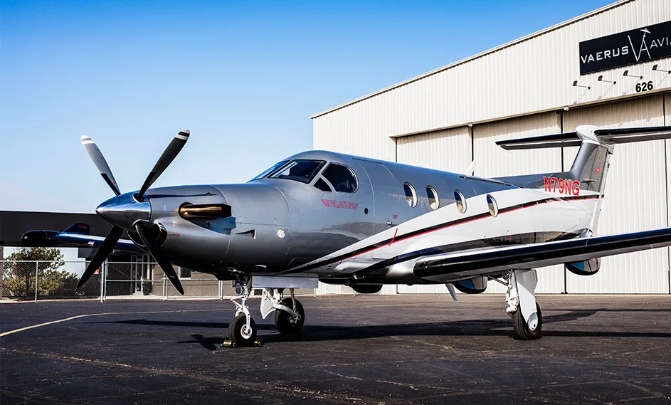 A Pilatus PC-12, registration N79NG, sits on the tarmac in front of a hangar.