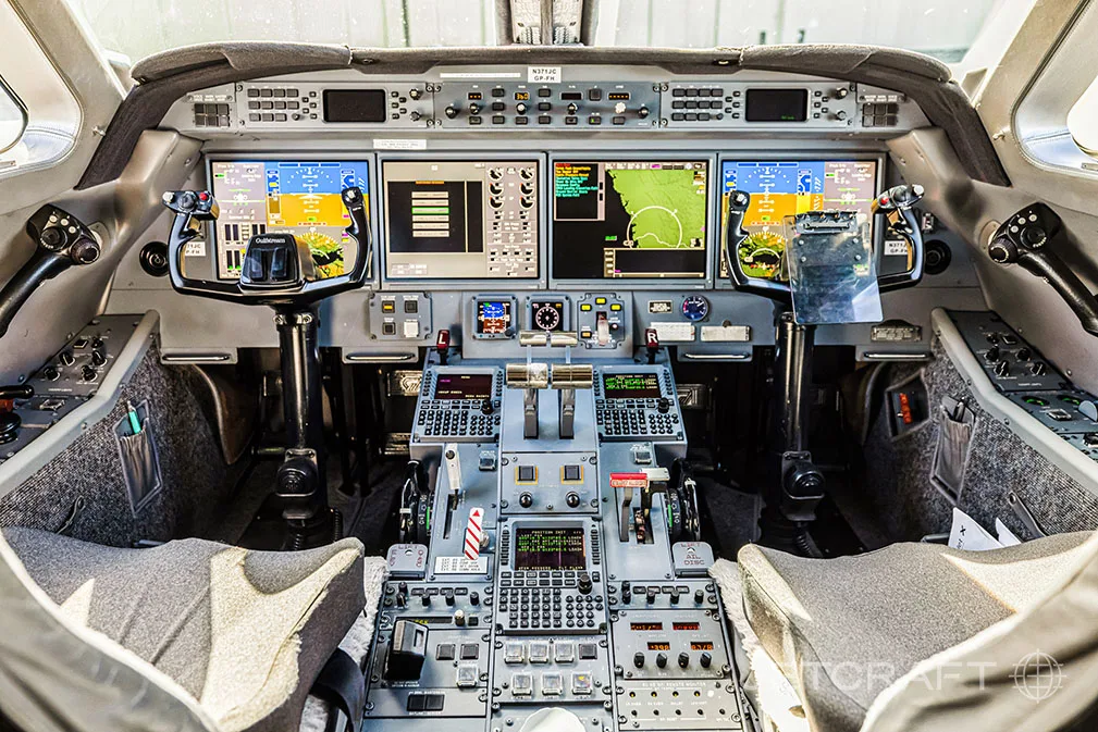 The modern glass cockpit of a Gulfstream G650, featuring multiple large display screens and control yokes.
