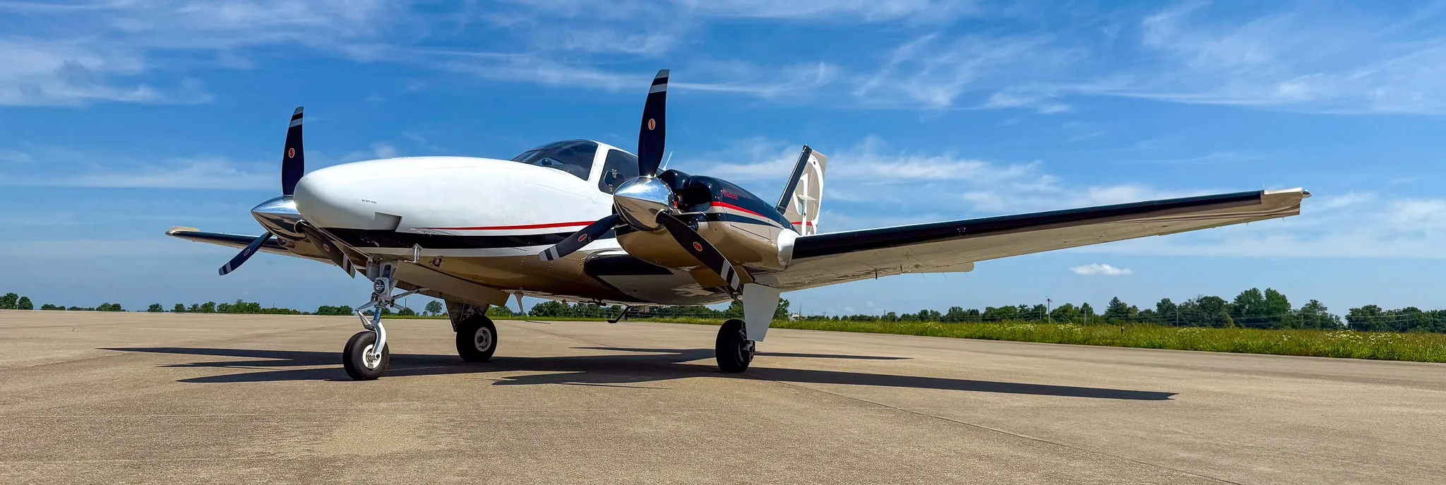 Low angle view of a white and gold twin-engine Beechcraft Baron G58 on an airfield.