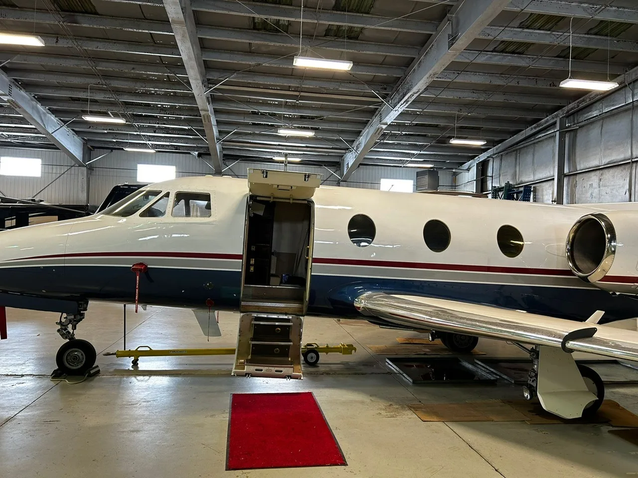 Close up side view of the aircraft N84TJ in a hangar with the door open.