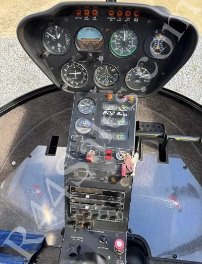 A close-up view of the instrument panel and controls in a Robinson R22 Beta helicopter.