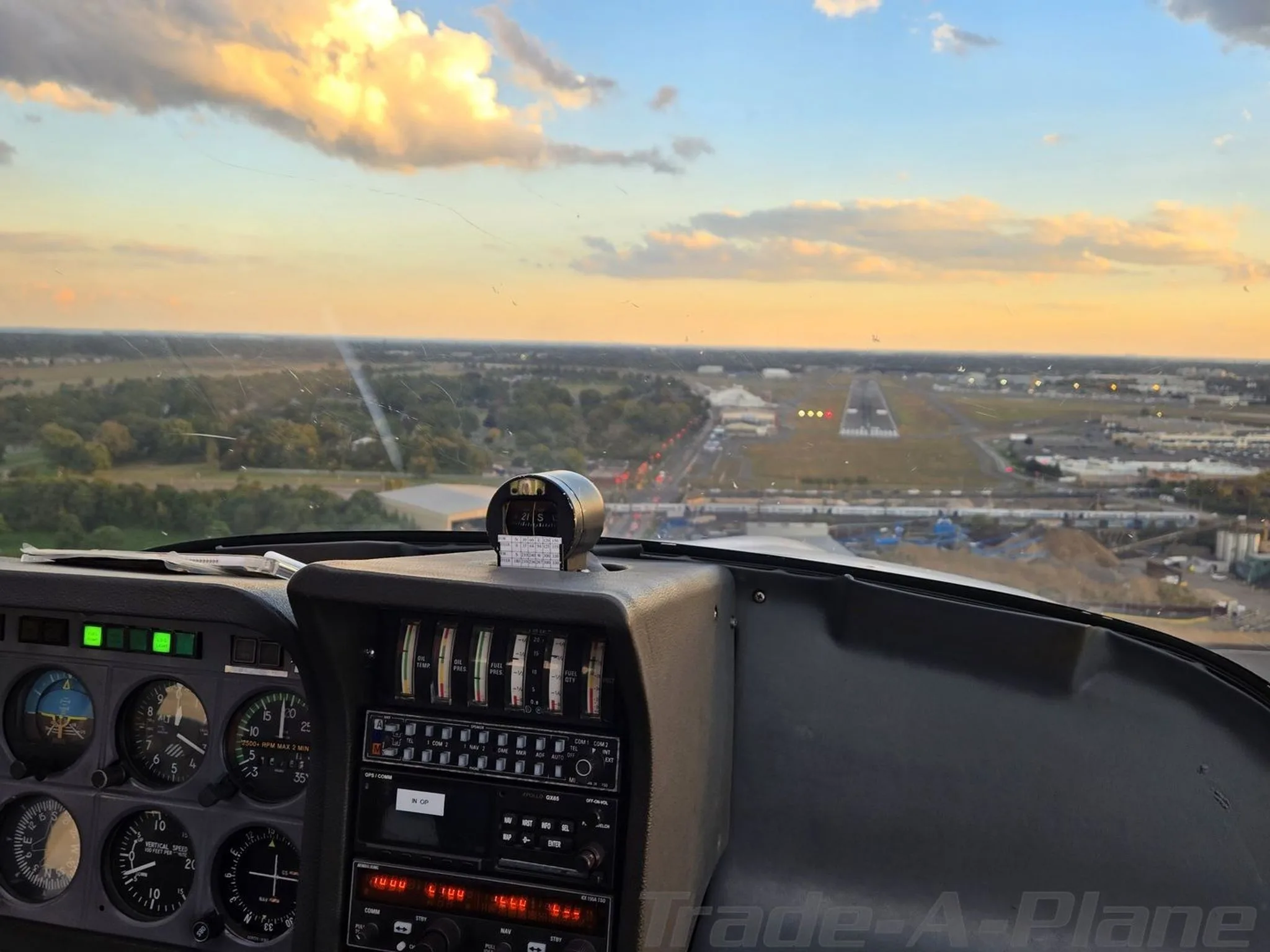 A view from the cockpit of the N130ER aircraft showing the instrument panel and a runway in the distance at sunset.