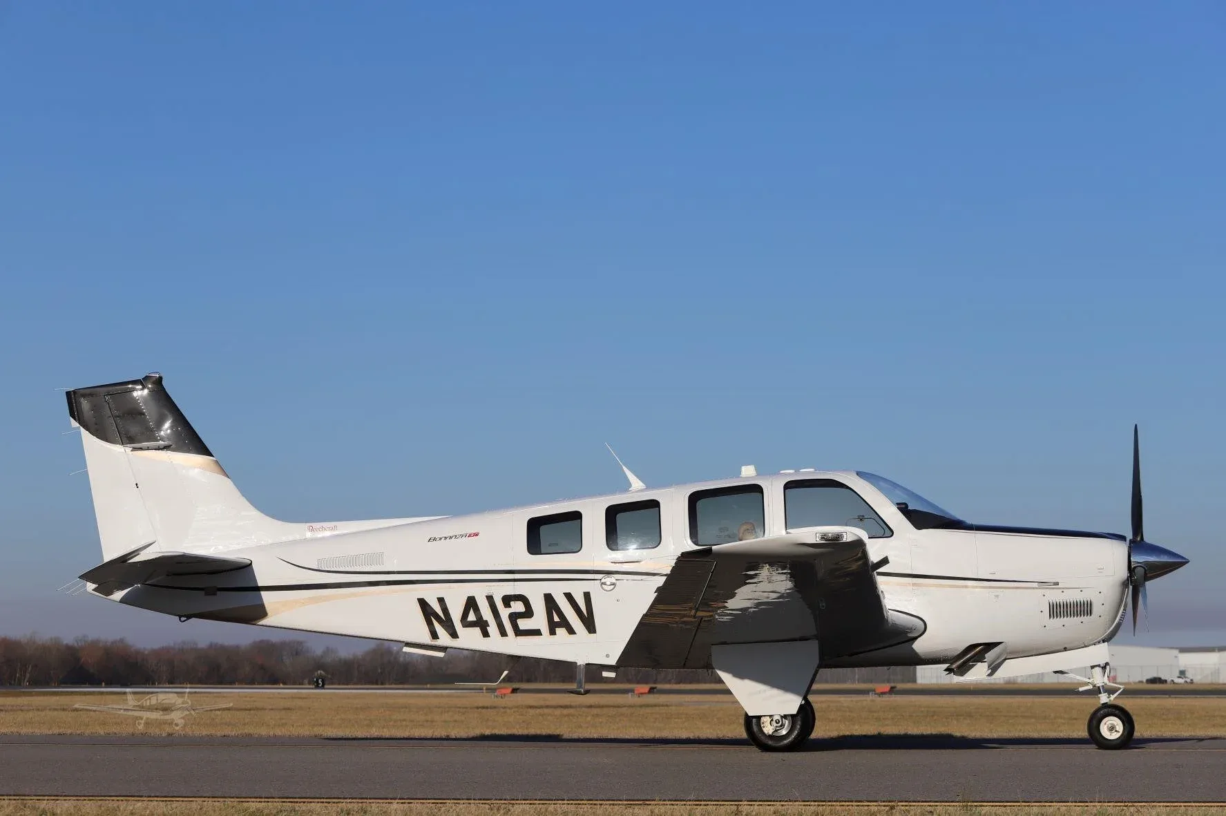 A white Beechcraft Bonanza G36, registration N412AV, seen from the side on a runway.