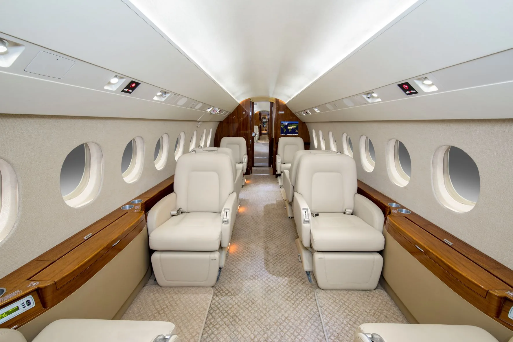 A luxurious aircraft cabin with light-colored leather seats and wood accents, looking towards the rear.