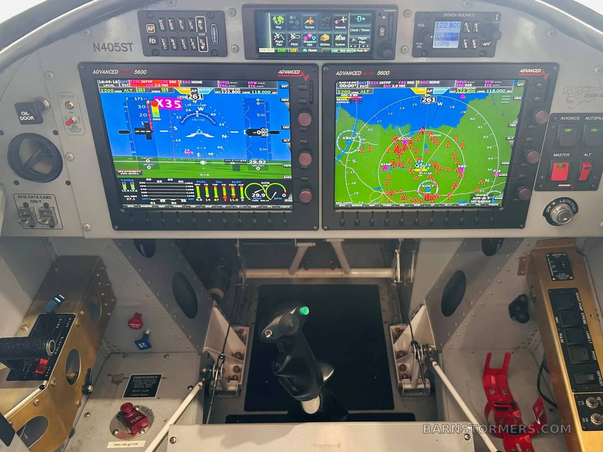The cockpit of an aircraft featuring two large digital displays showing flight information and a map, with various controls and switches.