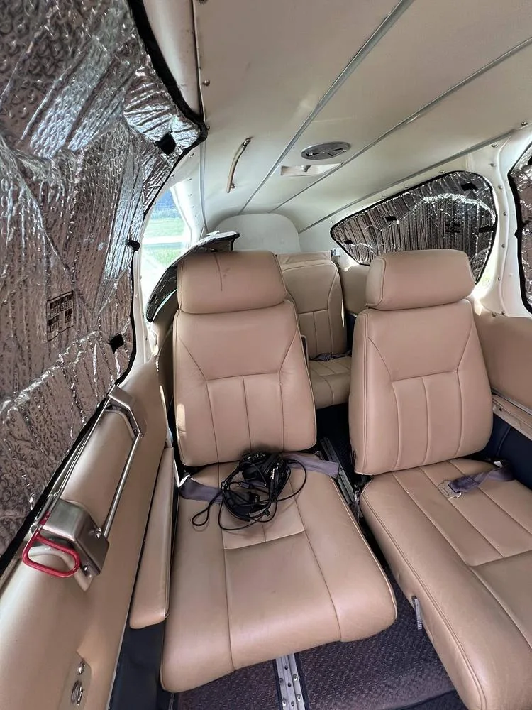 The aircraft's cabin interior features tan leather seats and reflective sun shades covering the windows.
