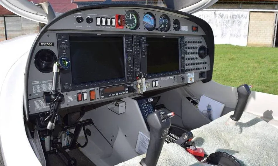 The cockpit of a Diamond DA40 aircraft with the canopy open, showing the instrument panel and controls.