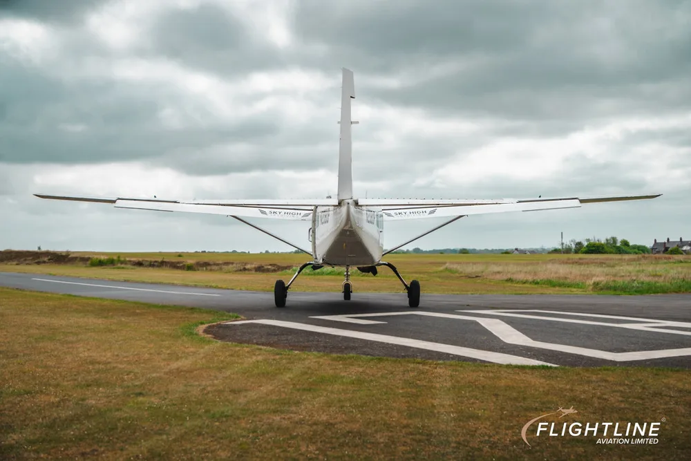 Rear view of a white Cessna 208 Caravan with N208UP registration, parked on a runway.