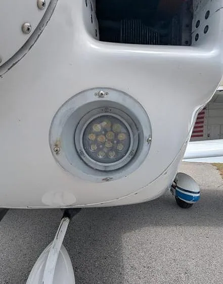 A close-up view of an LED landing light and the nose gear strut of the Grumman AA-5 Traveler.