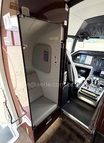 A view from the cabin looking into the modern glass cockpit of the Embraer Praetor 600, with a small seat to the left.