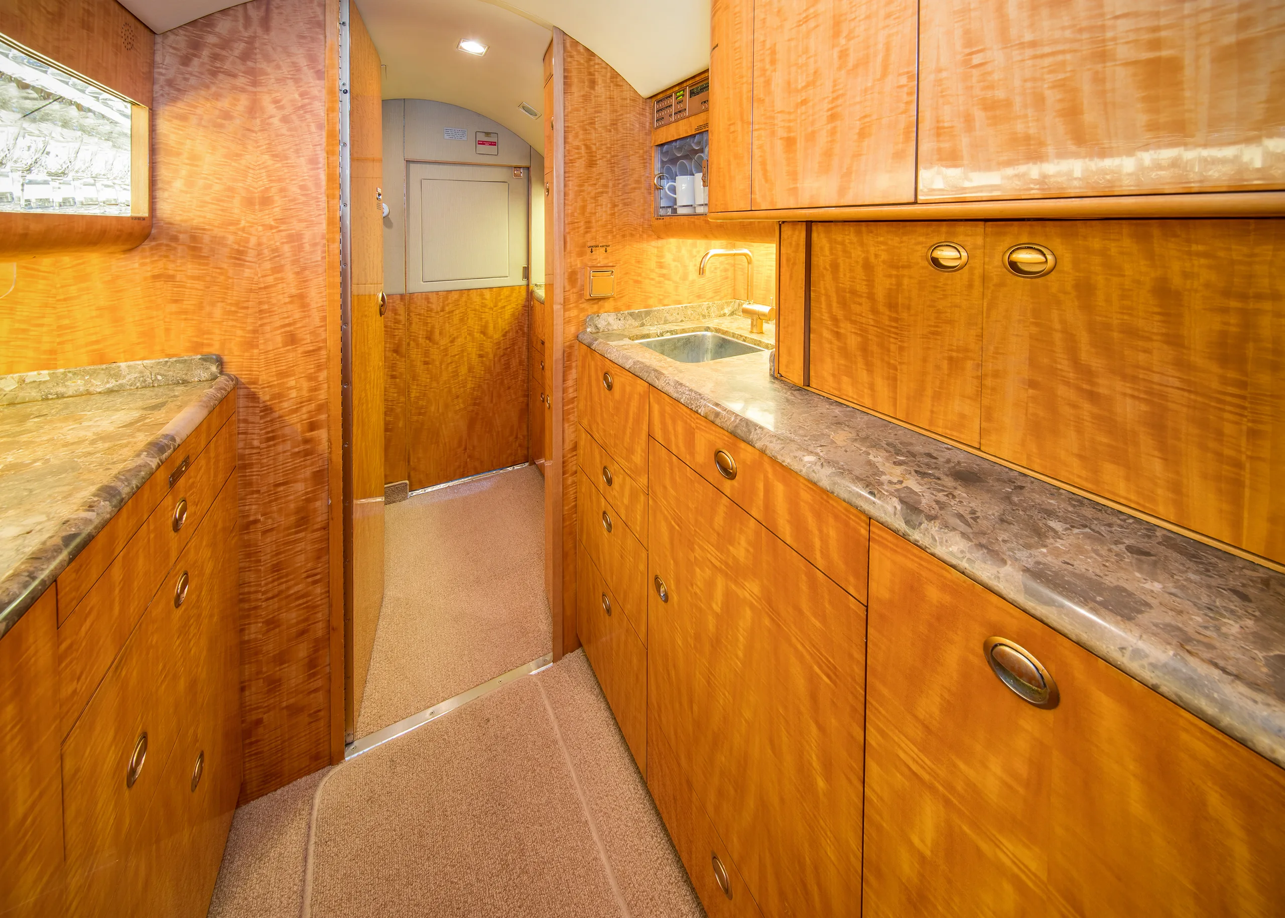 The aircraft's interior features a galley area with cabinets and a sink.