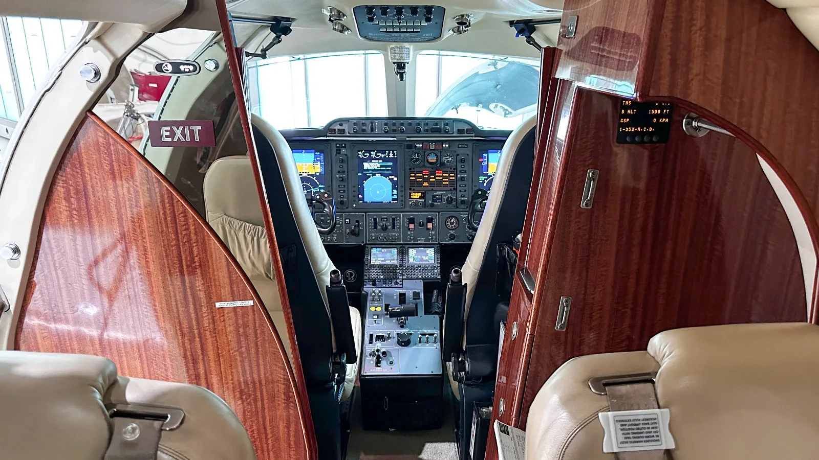 View from the cabin into the cockpit of a business jet, showing the instrument panel and controls.