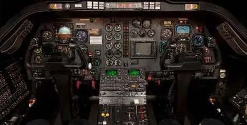 A detailed view of a dark aircraft cockpit with numerous analog gauges, digital displays, and control panels.