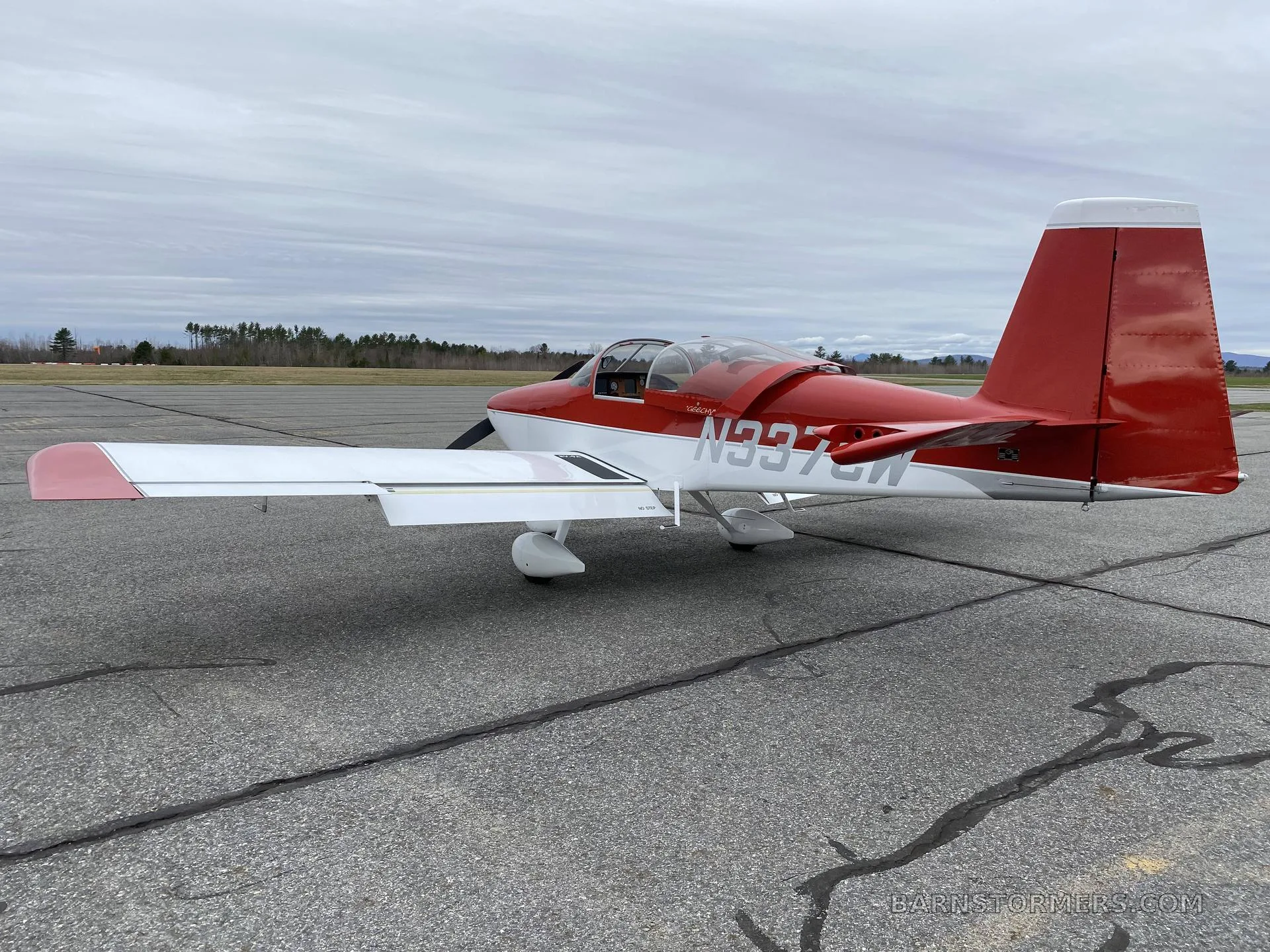 A red and white experimental aircraft with registration N337CW is parked on an airfield, viewed from the rear-right.