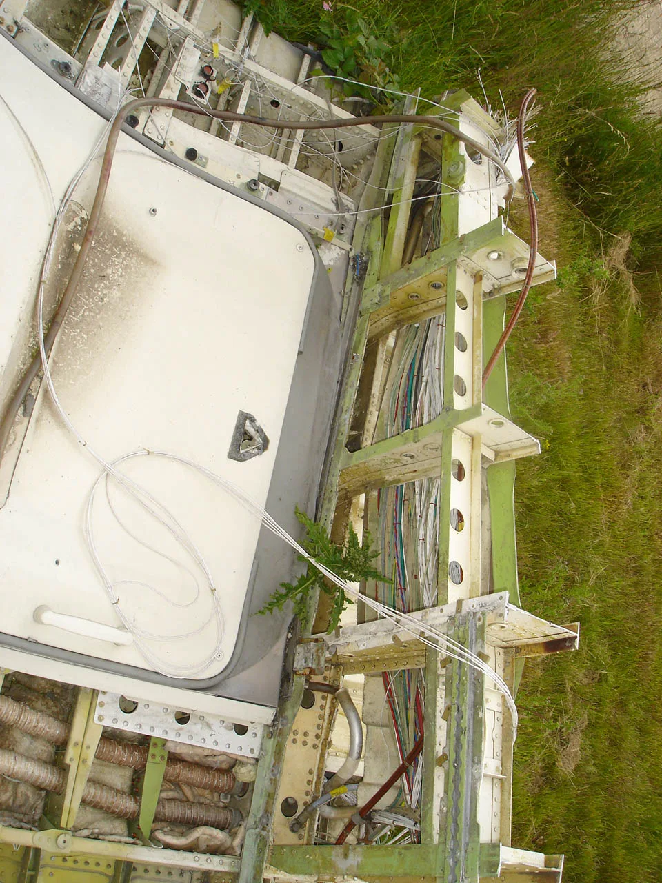 A detailed view of exposed wiring and structural components within a disassembled aircraft fuselage section.