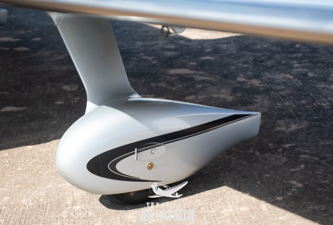 A close-up view of the Cirrus SR22 aircraft's silver main landing gear fairing with a black stripe.