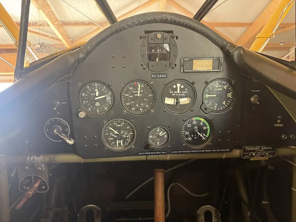 A close-up view of the instrument panel in the cockpit of a Stearman biplane, showing various gauges and N1344V.