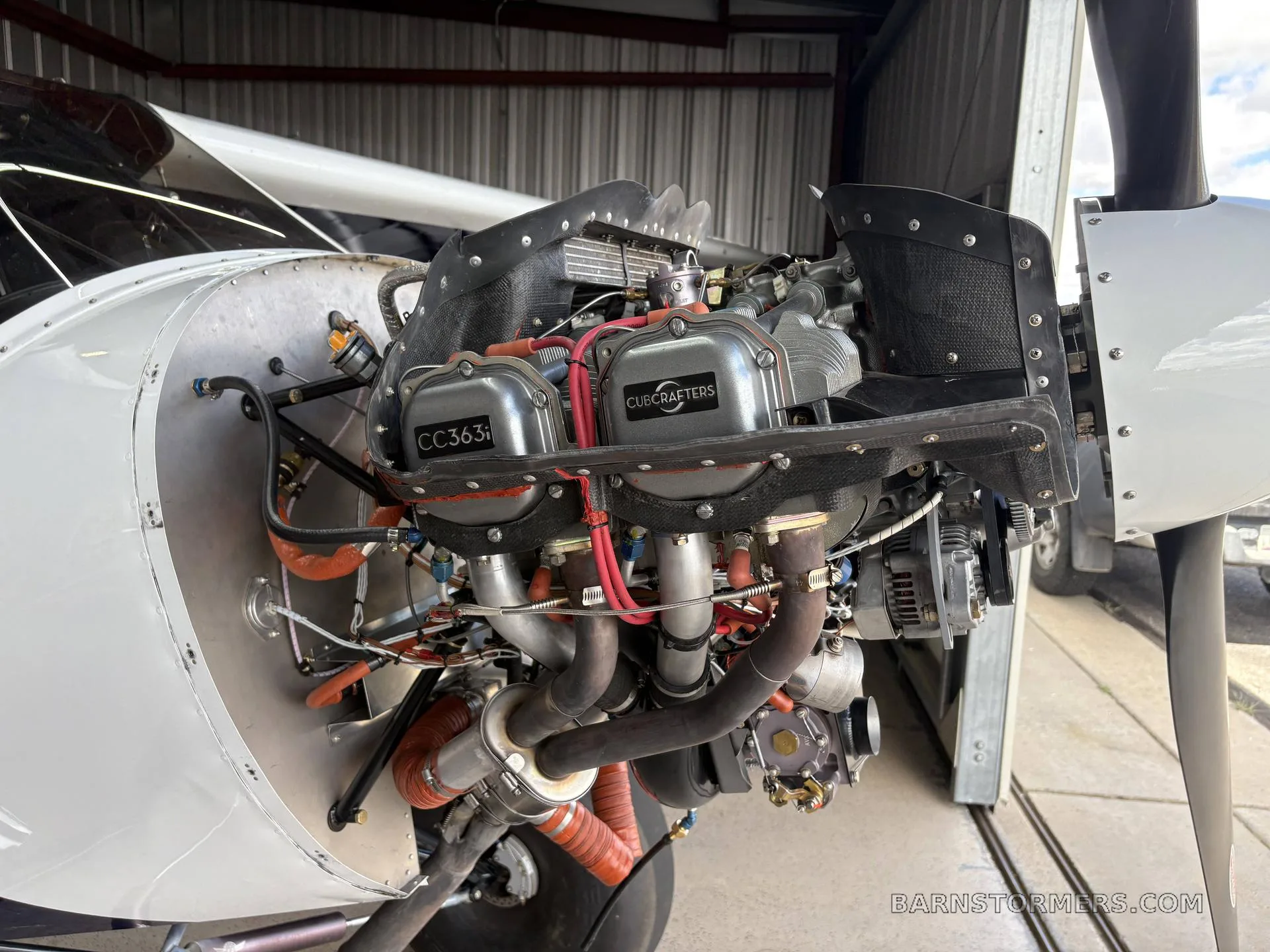 A close-up view of the CubCrafters CC363i engine installed in an aircraft, showing cylinders and exhaust.