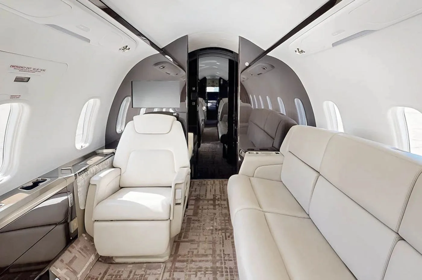 The private jet's cabin interior featuring a cream-colored sofa and individual white leather seats.