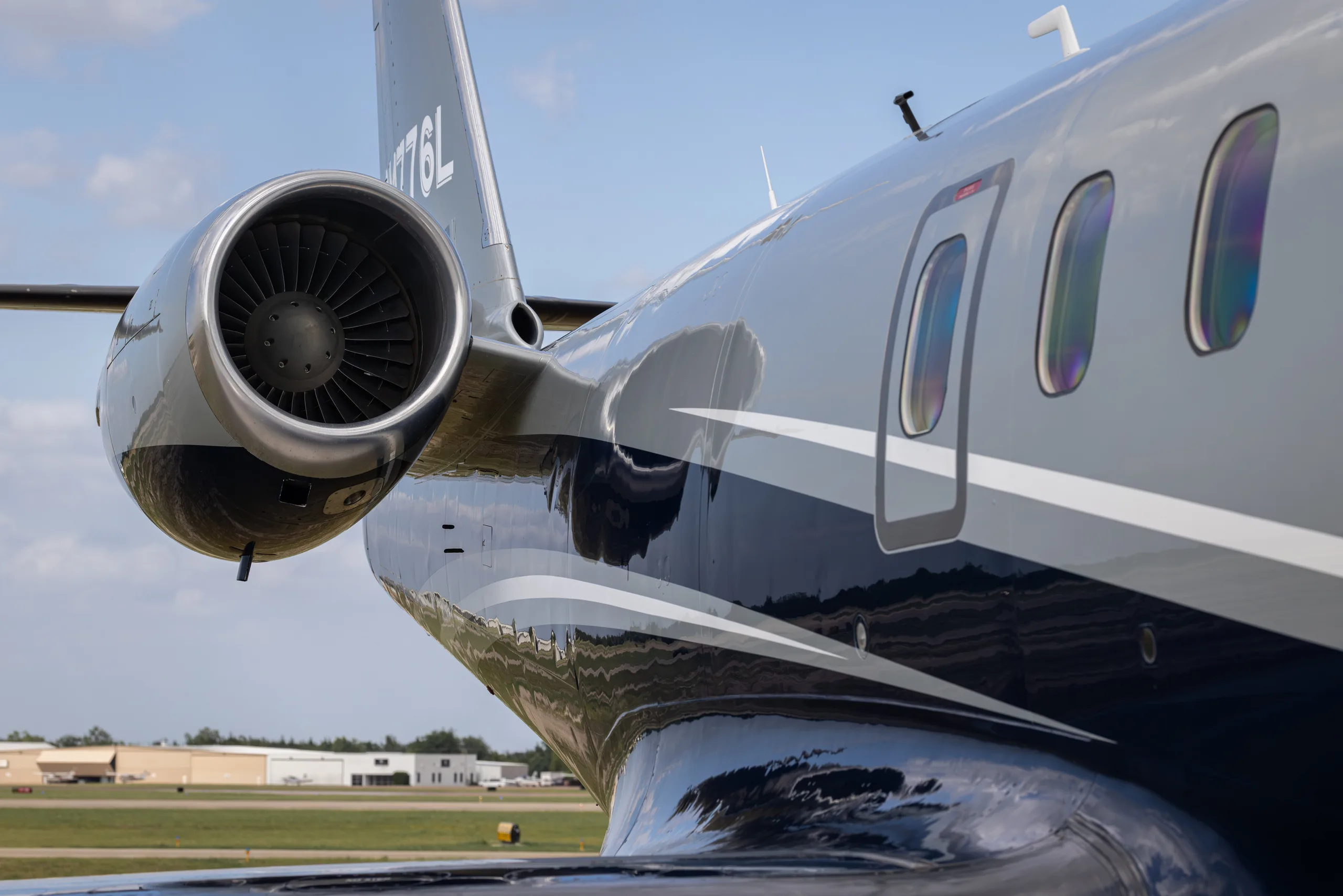 A close-up view of the rear fuselage and engine of a Learjet 60, showing its grey and dark blue paint scheme.