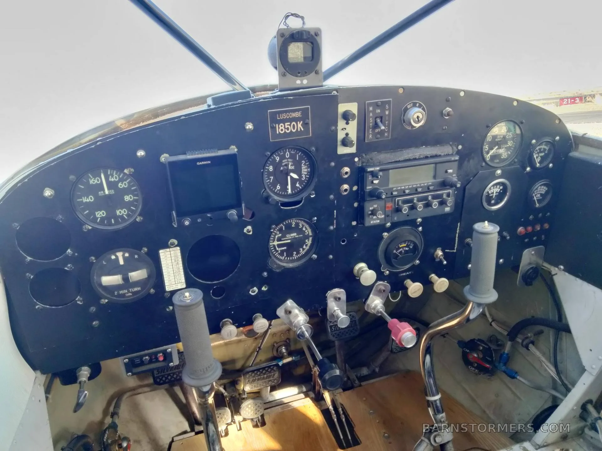 The cockpit instrument panel of a Luscombe 1850K aircraft, featuring various gauges, a Garmin GPS, and controls.