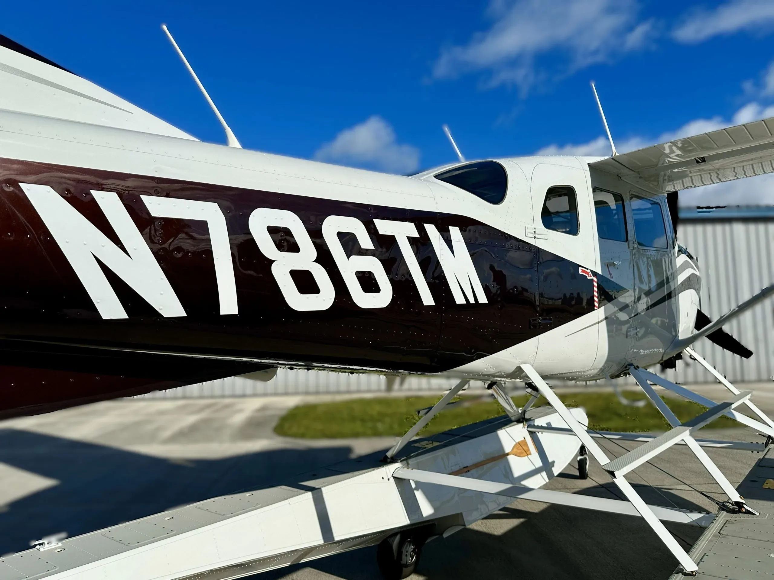 The side fuselage of Cessna Stationair HD N786TM, showing its white and dark brown paint scheme.