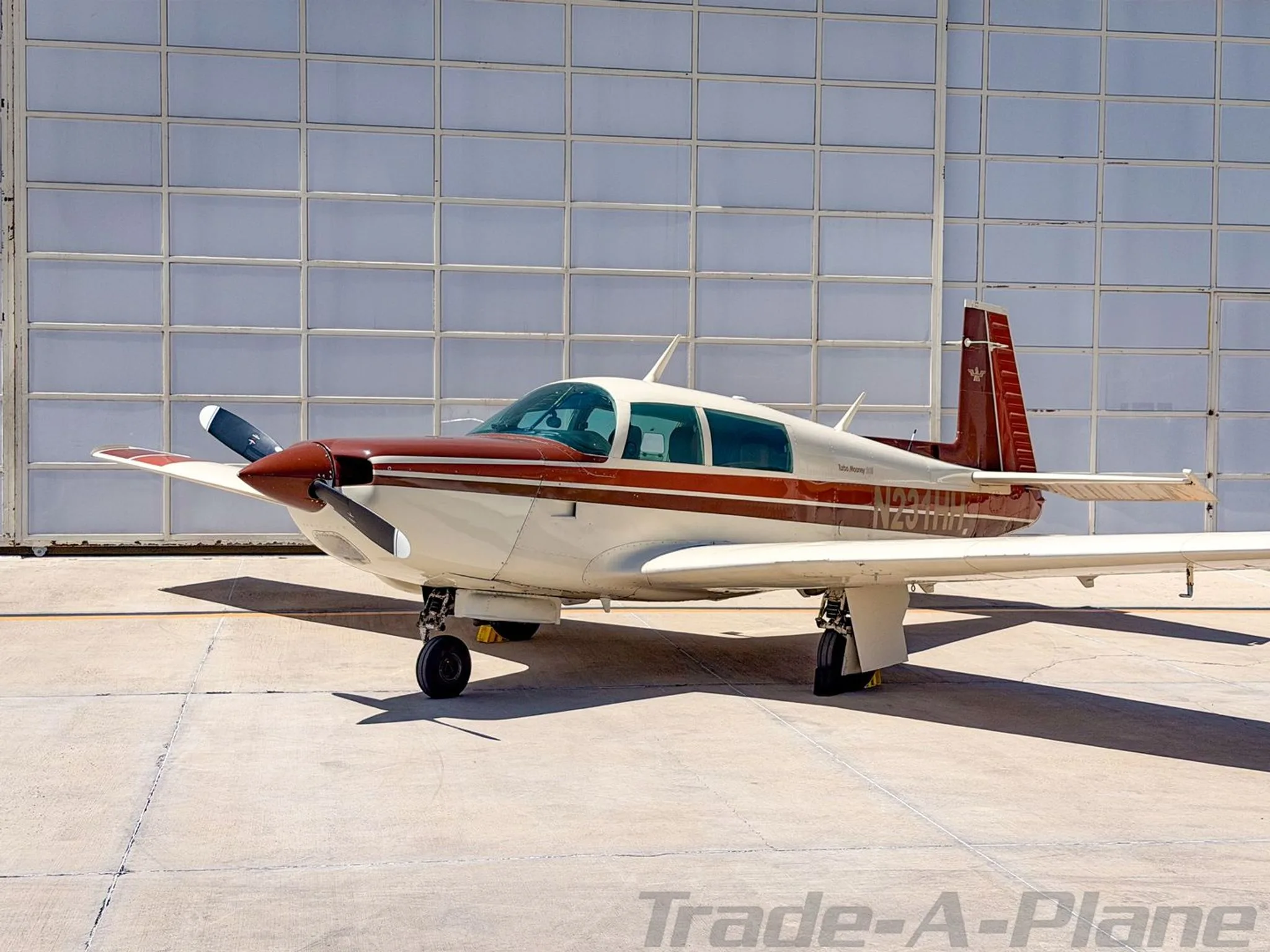 A Mooney M20K 231 parked in front of a hangar.
