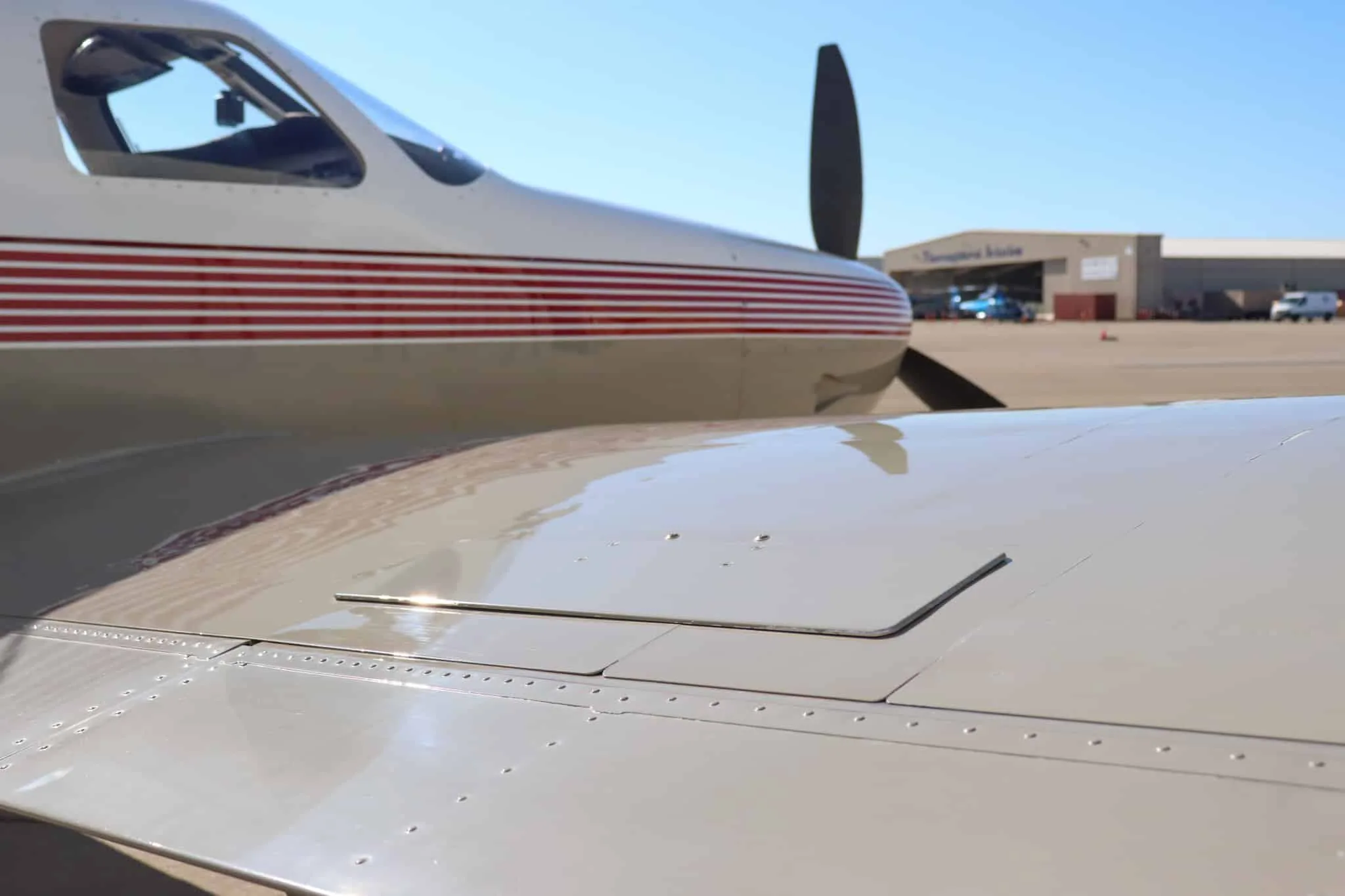A close-up view of the tan wing and white fuselage of the Piper Malibu Mirage N463WB, showing the red stripe detail.