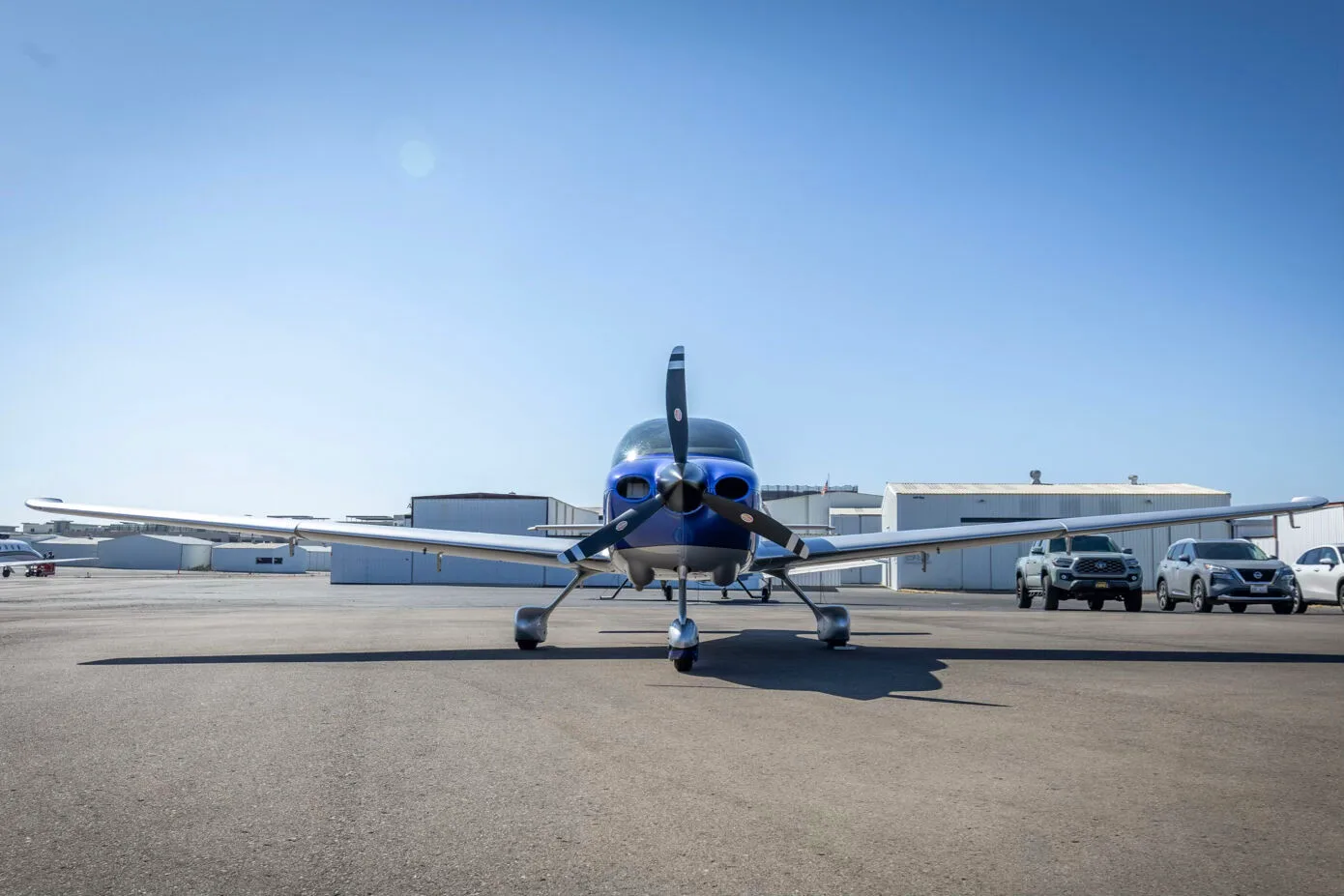 A front view of the blue and silver Cirrus SR22 aircraft, N275MG, parked on an airport tarmac.