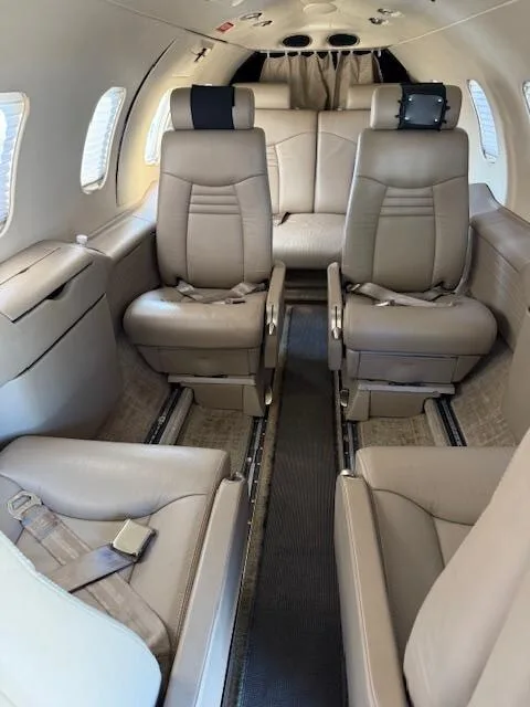 The aircraft's cabin interior with tan leather seats arranged in a club configuration.