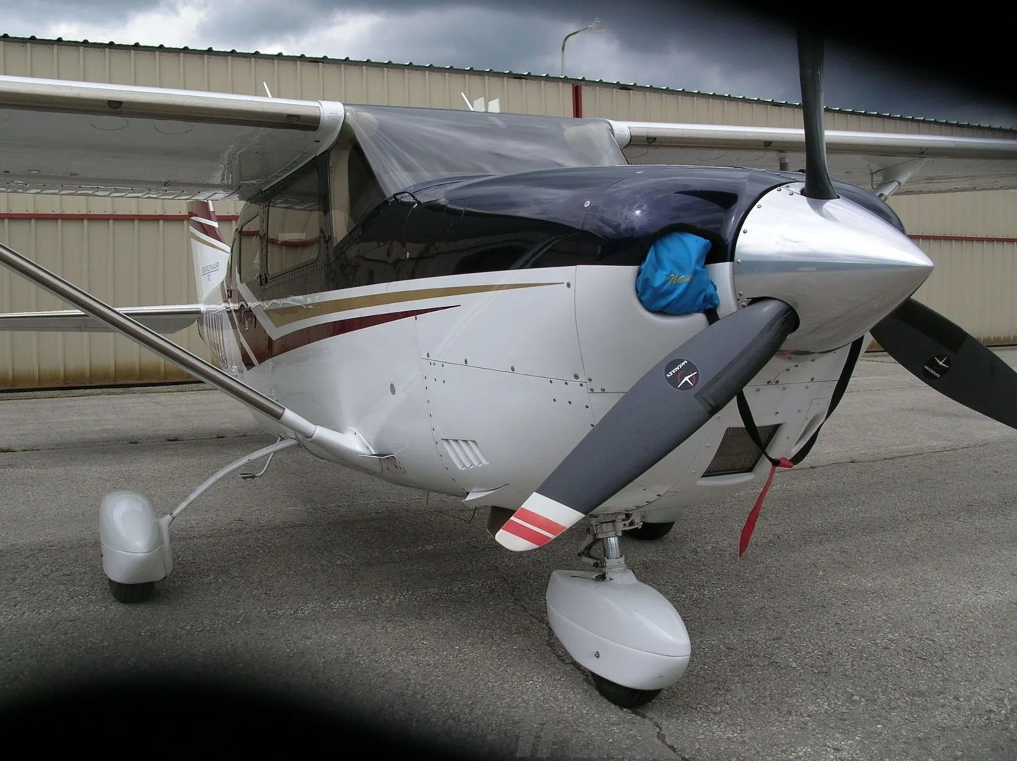 A front-quarter view of a white Cessna Stationair TC with dark blue and maroon stripes, registration N444VX, showing the propeller and nose.