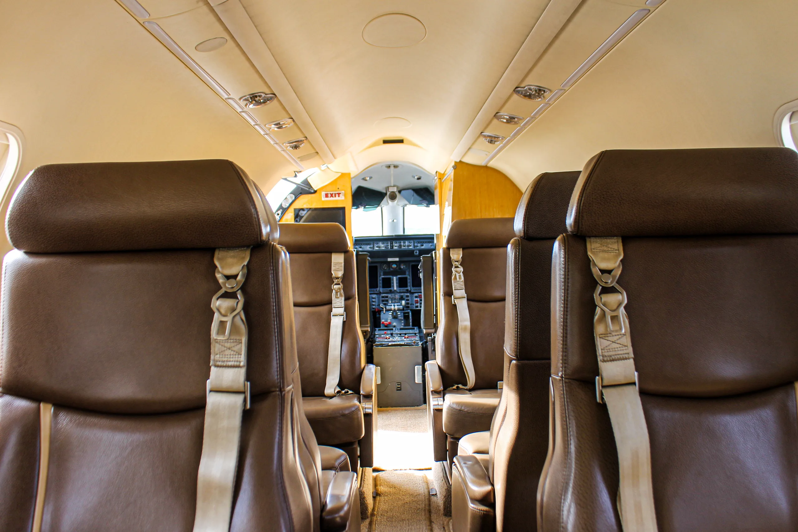 View of the aircraft cabin interior with brown leather seats looking towards the cockpit.