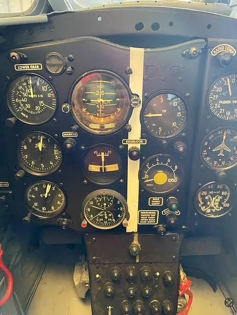 A close-up of a vintage jet aircraft's instrument panel, displaying numerous gauges and warning labels.